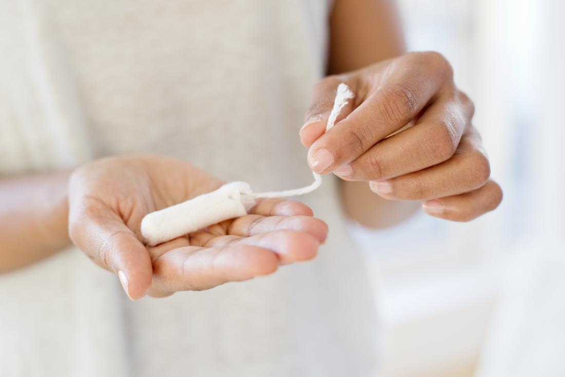 Woman with tampon in hand hoping to stop periods after they have started