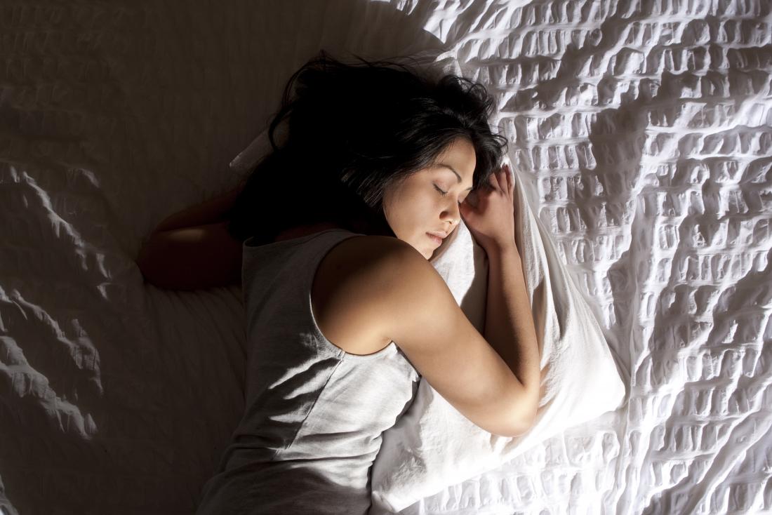 Woman sleeping on her left side in bed.