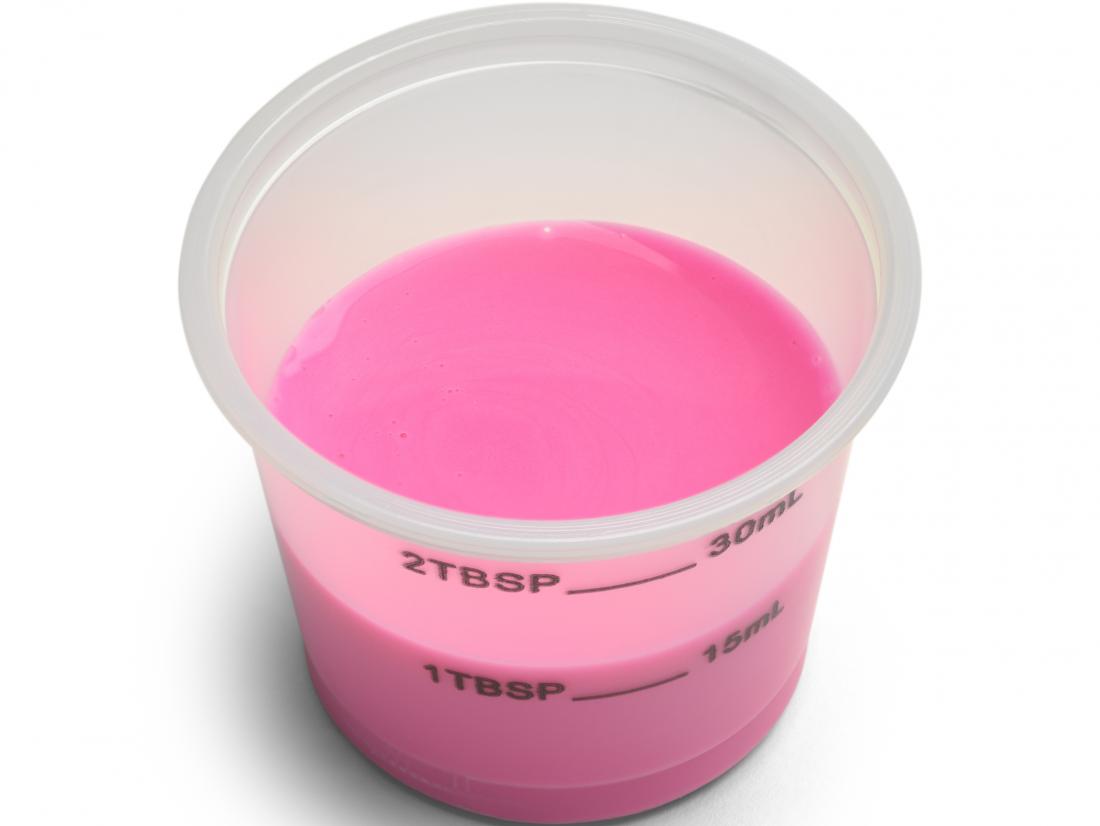 Pink medicine pepto-bismol in measuring cup