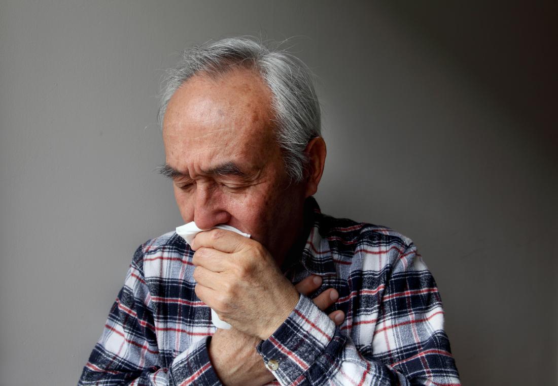 Senior man with COPD coughing into tissue.