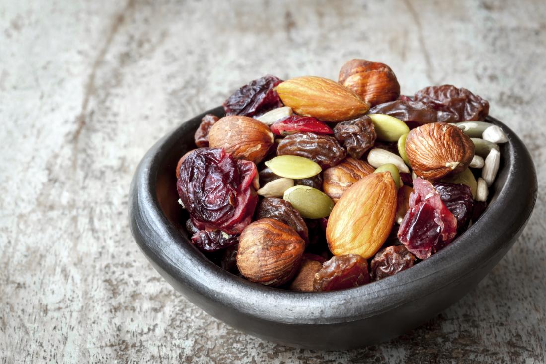Trail mix in small bowl, with cranberries, almonds, seeds, and hazelnuts.