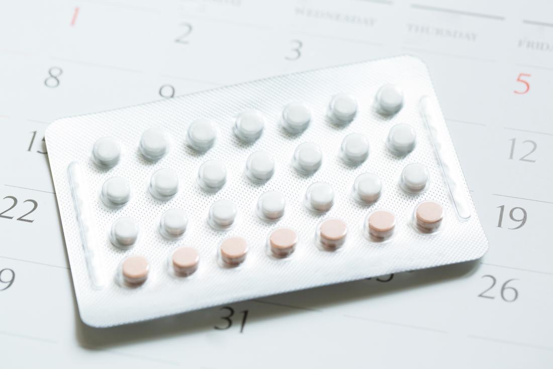 Packet of birth control pills on top of calander