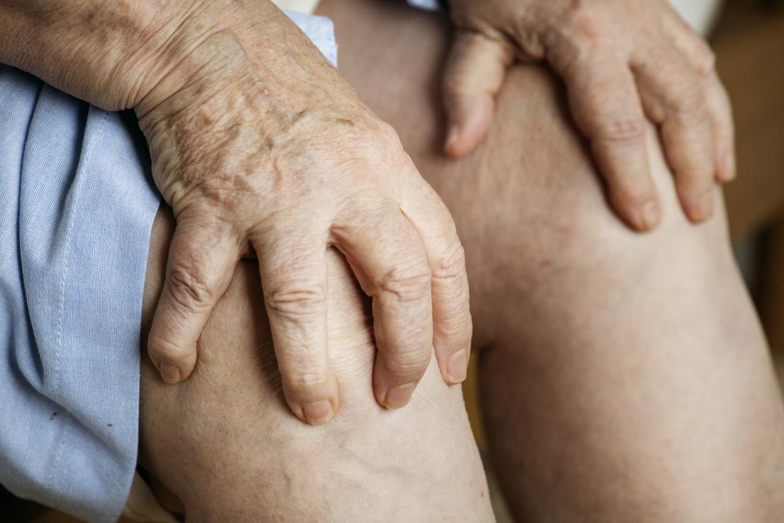 Senior person hands holding knees representing difference between gout and arthritis