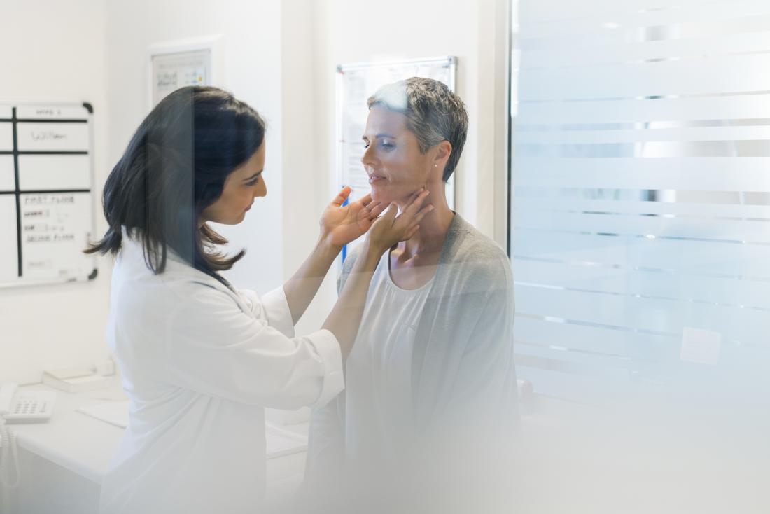 Doctor checking female patients thyroid glands