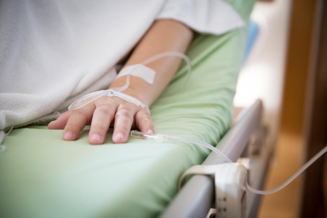 Patient in hospital bed with saline drip receiving chemotherapy