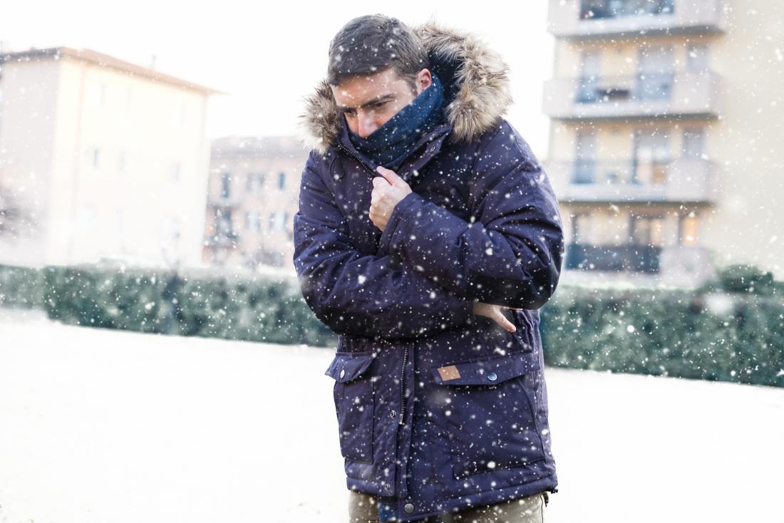 Person outdoors in snow with coat on shivering in cold weather