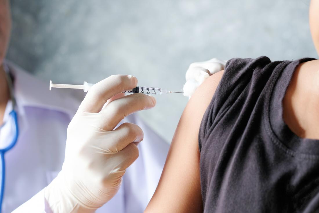 Woman receiving injection of vaccine shot in arm.