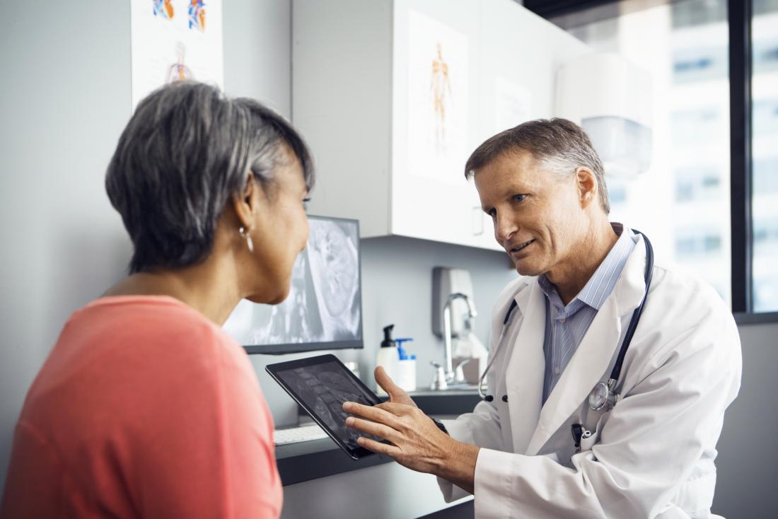 Doctor speaking to patient in office while showing them a tablet