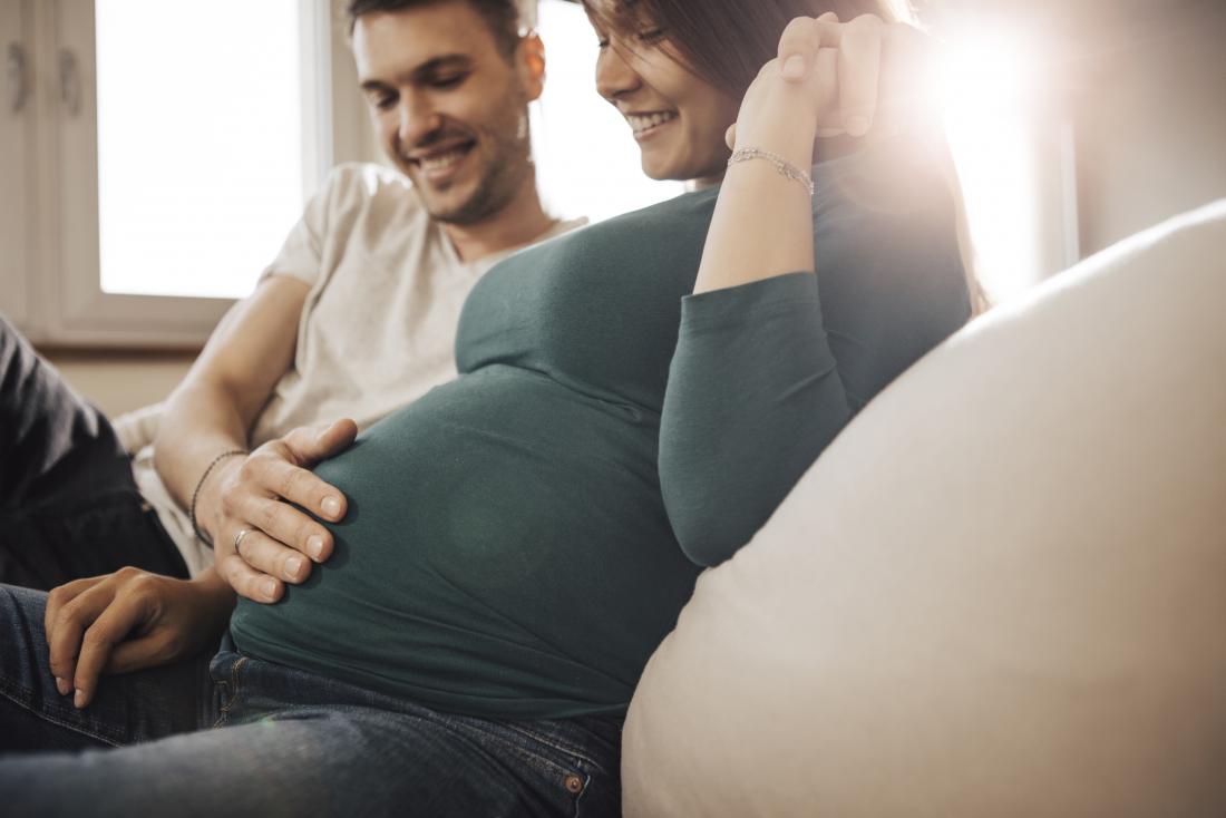 pregnant couple holding baby bump to feel flutters