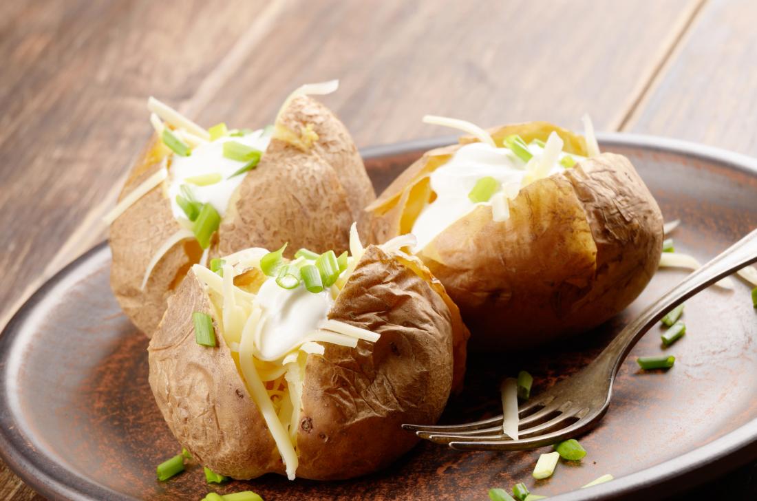 Baked potatoes on plate with chive, sour cream, and cheese filling