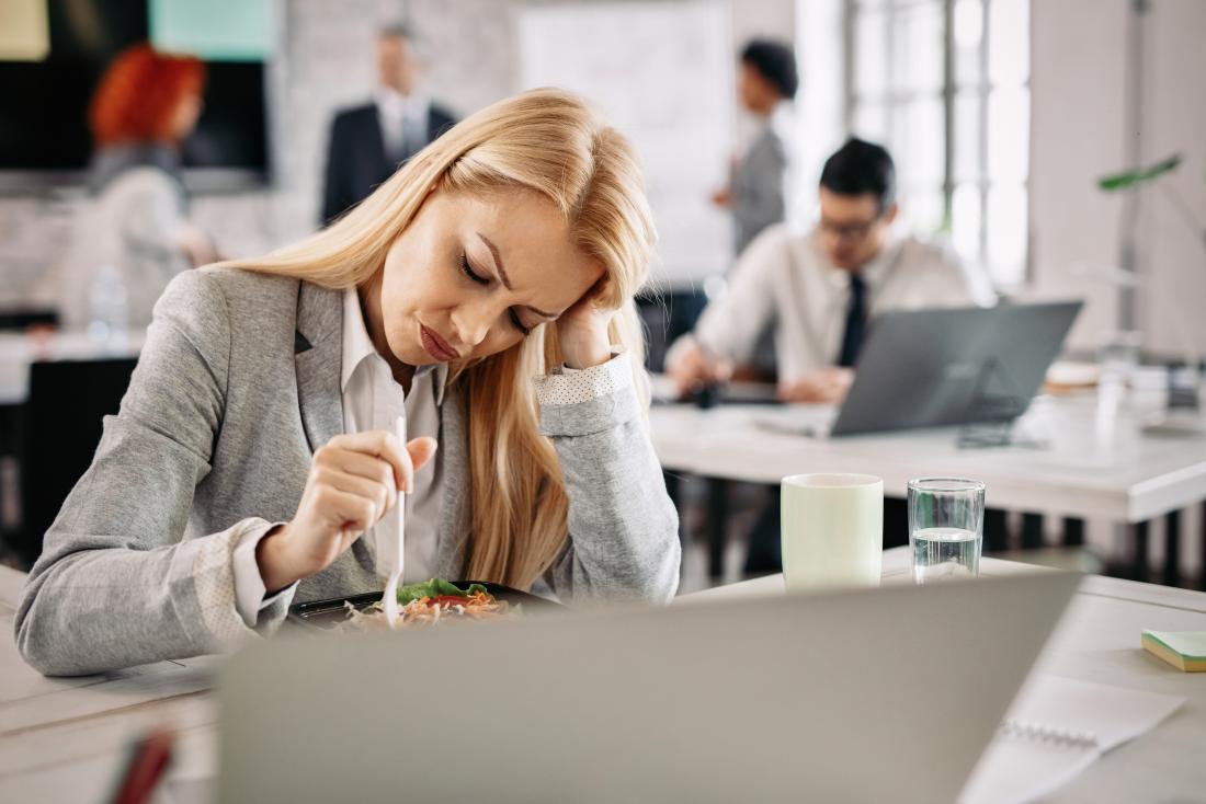 Woman struggling with food at her desk due to pregnancy