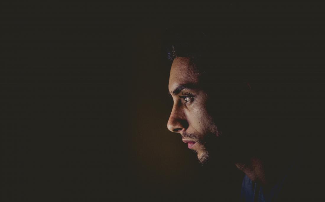 profile of sad man on dark background
