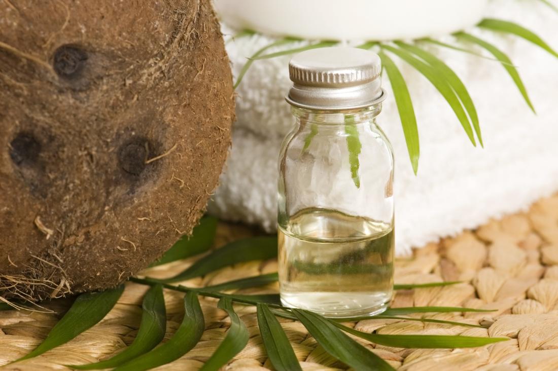 Coconut oil in small glass jar next to towels and leaves.