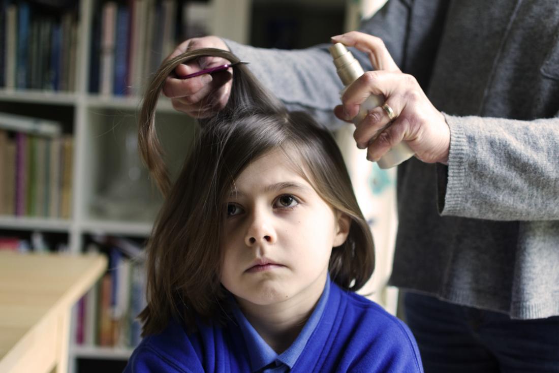 Head lice treatment being applied to a young girls hair