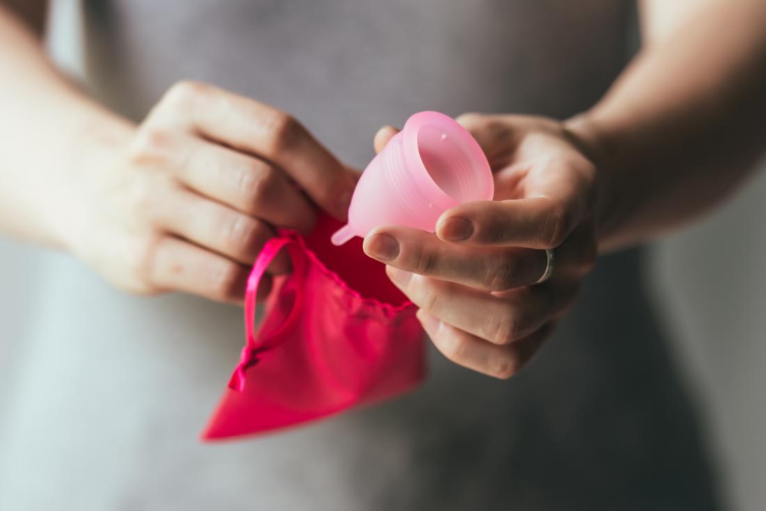 Woman holding menstrual cup with pouch.