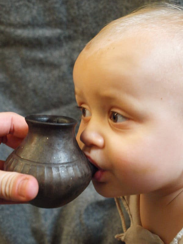 A baby drinking from a reconstructed vessel like those found in the graves of infants in Bavaria.