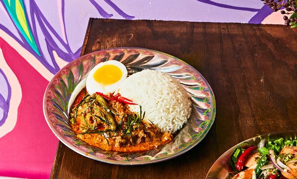 Panang curry is served with half an egg, fresh chiles and threads of lime leaf.