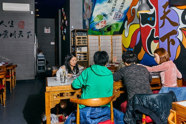 The restaurant is a mix of old and new, with concrete floors and carved furniture alongside a psychedelic mural of traditional Beijing opera masks.