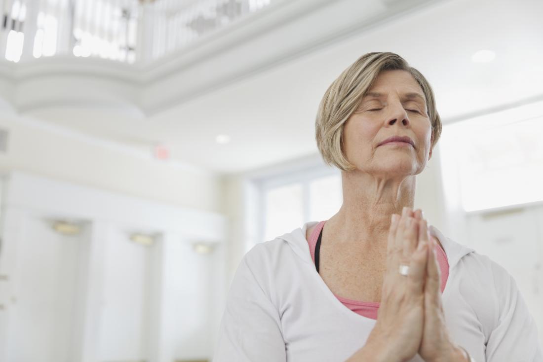 Mature woman doing yoga and meditation with breathing exercises.