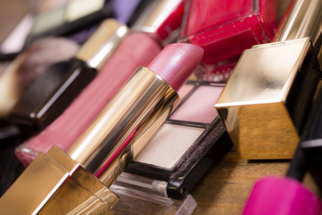 Cosmetics piled on table, including lipstick and lip gloss as well as eye shadow
