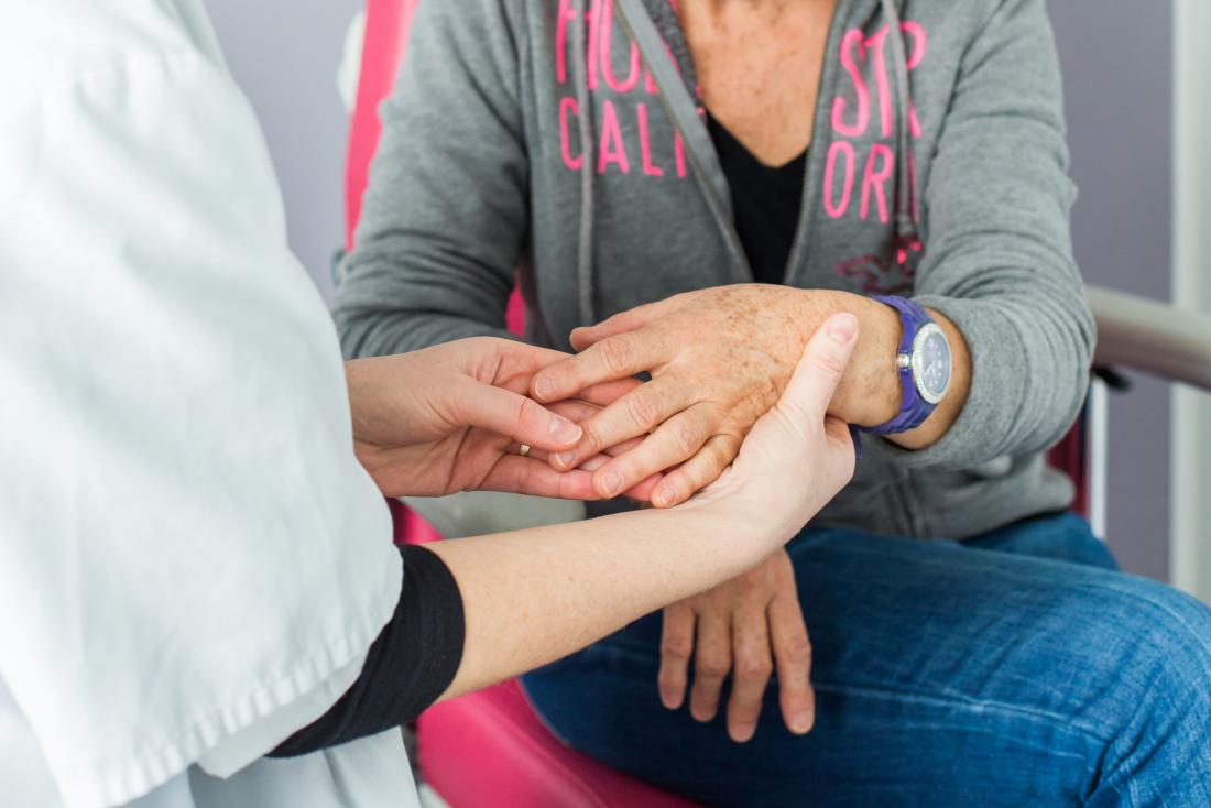 Nurse or rheumatologist inspecting female patients hand for rheumatoid arthritis.