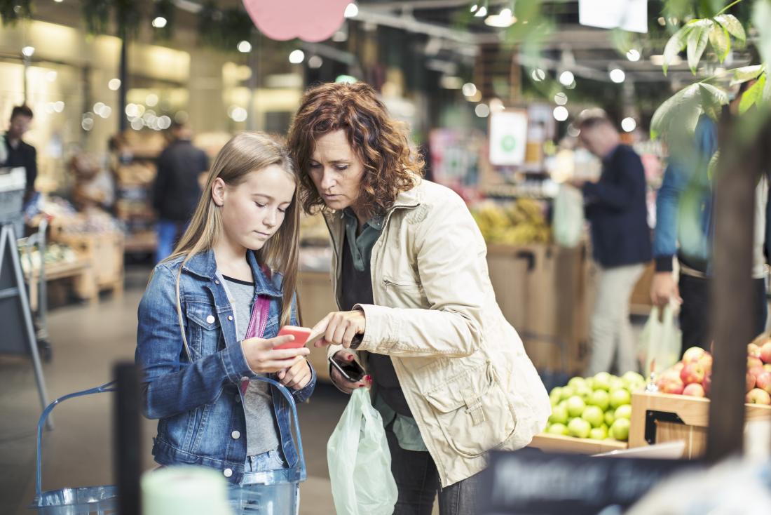 Mother and daughter in supermarket looking at phone
