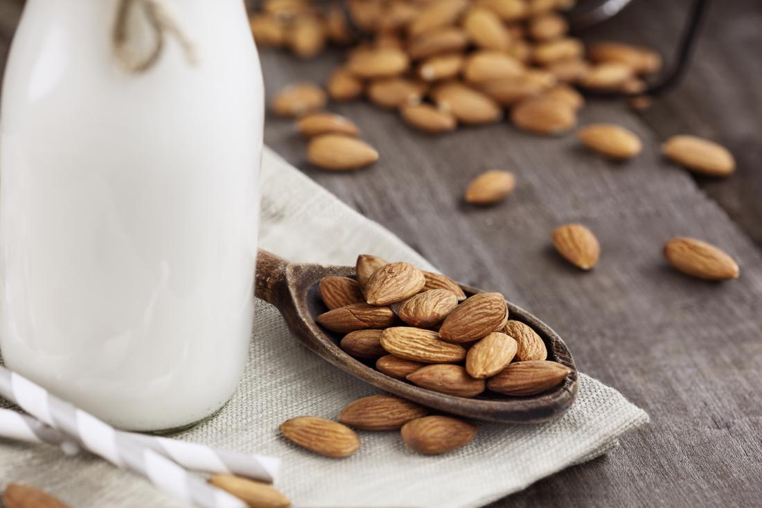 Almonds on a wooden spoon and almond milk
