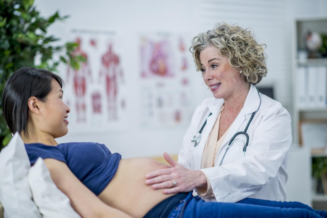 Pregnant woman in second trimester visiting with her doctor