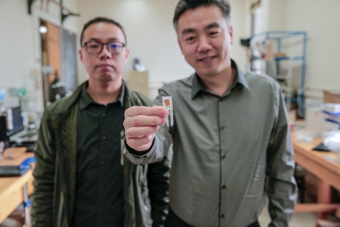Graduate student Guang Yao (left) and Xudong Wang (right) hold a small implantable device. Image credit: Sam Million-Weaver
