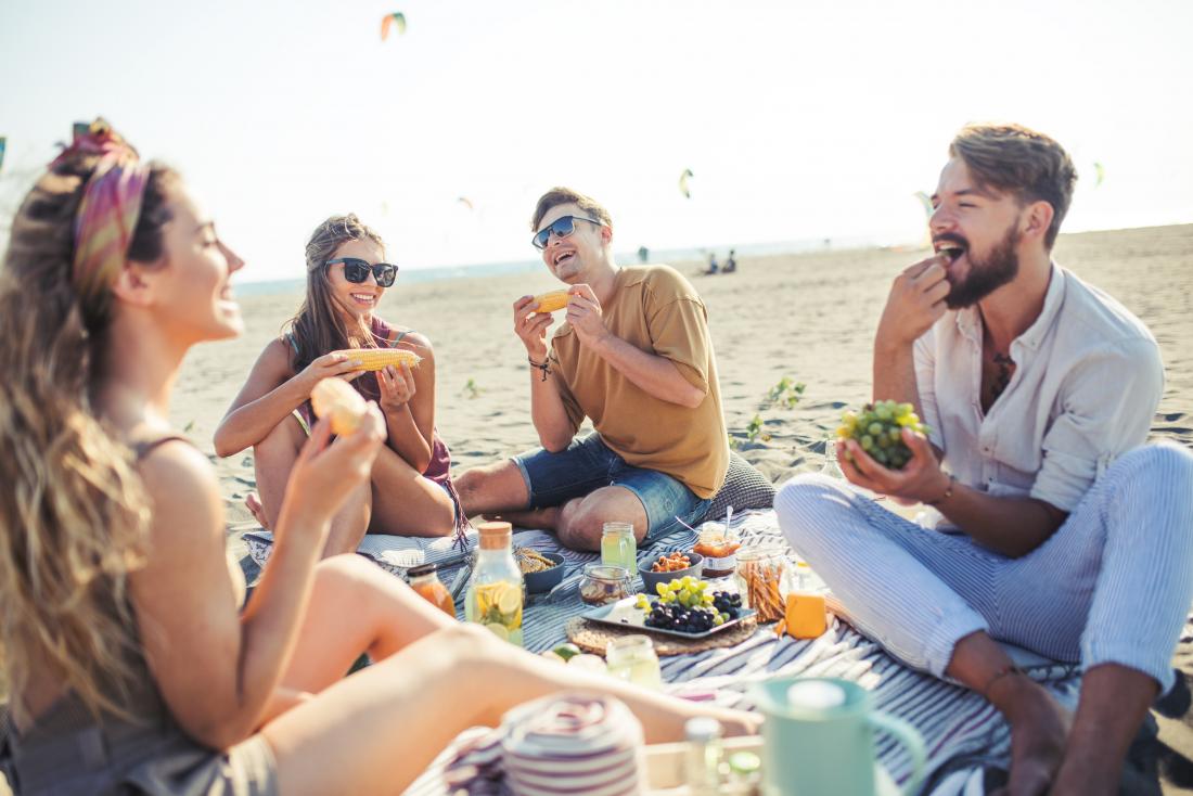group of friends eating picnic on beach