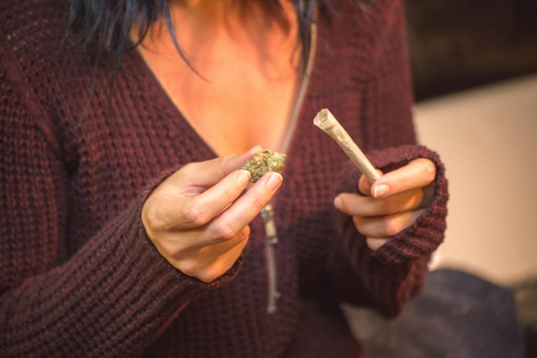 Woman holding marijuana bud and cannabis joint for smoking weed