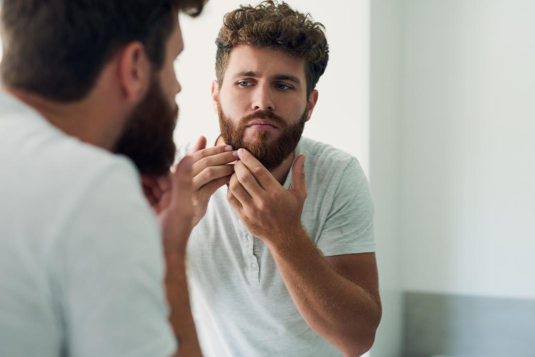 Man inspecting beard in mirror