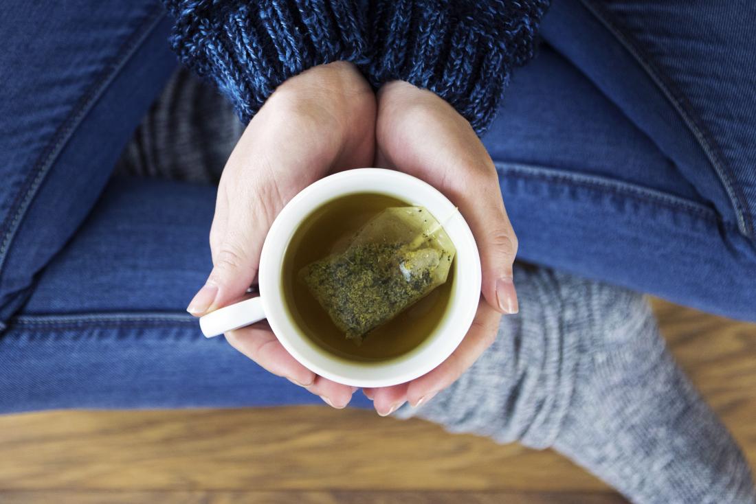 Woman holding a cup of herbal tea which can help with menstrual cramps