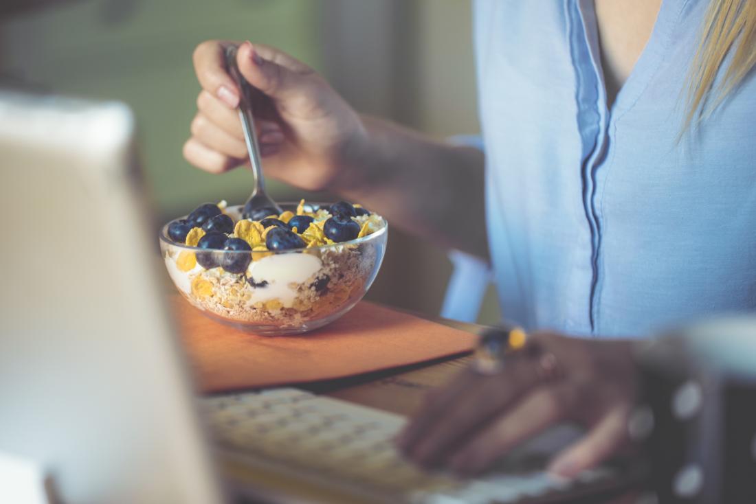 person eating breakfast bowl with blueberries