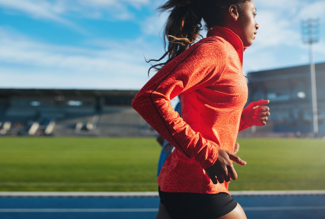 woman using bcaas supplement running on racing track
