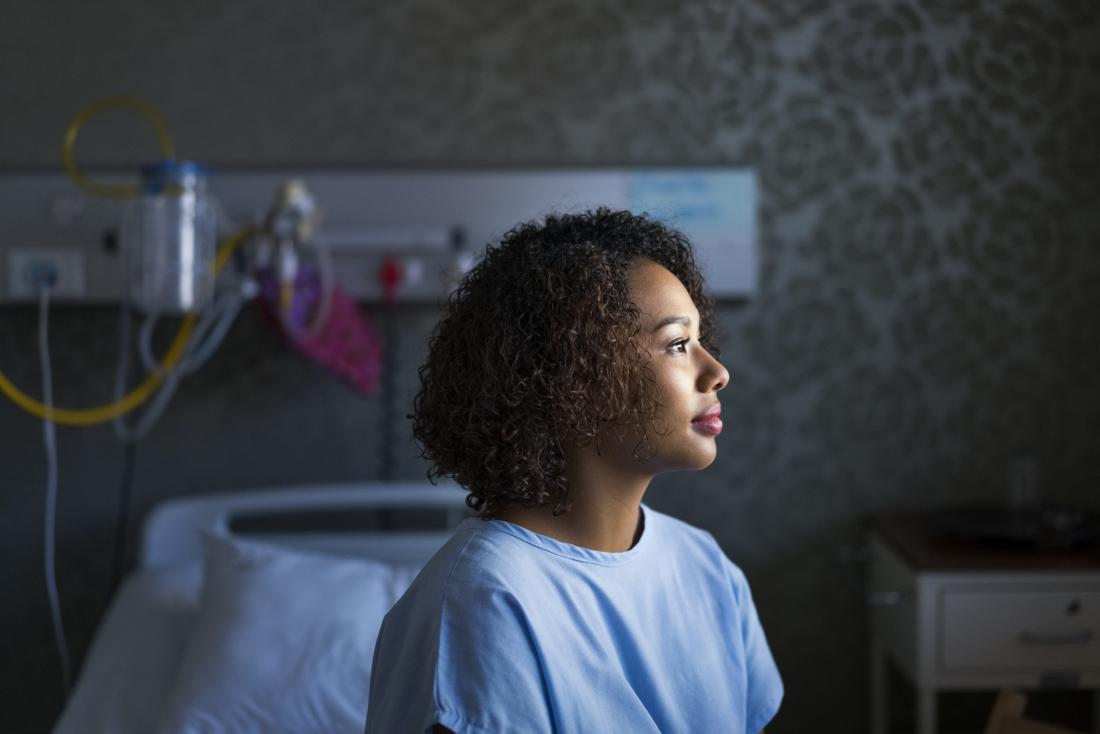 woman sitting on hospital bed, looking hopeful, seen from profile