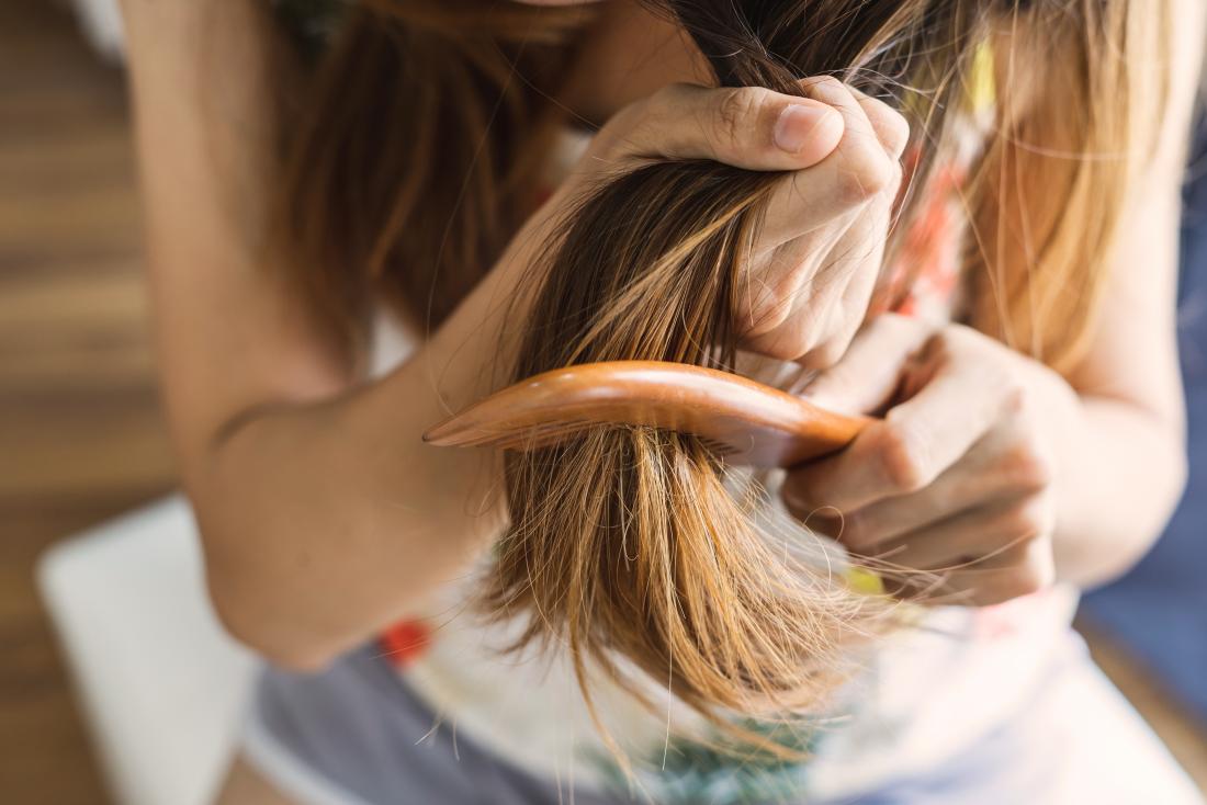 Woman brushing her hair which can cause hair breakage