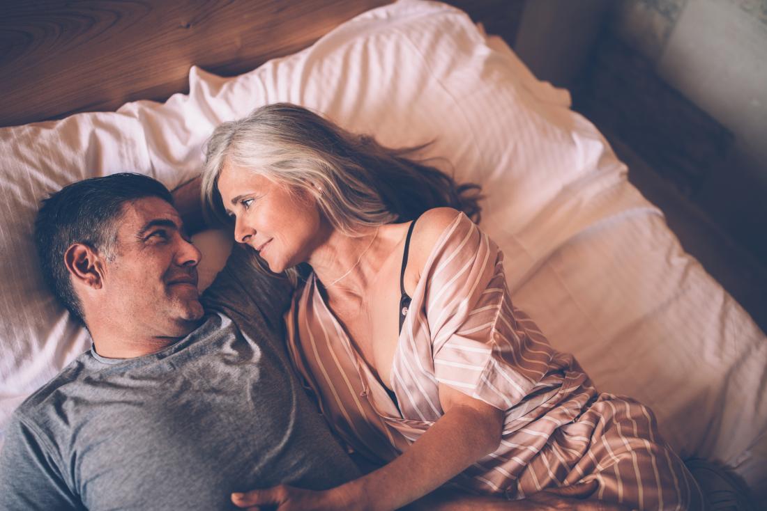 Mature couple experiencing loss of libido lying in bed looking at one another