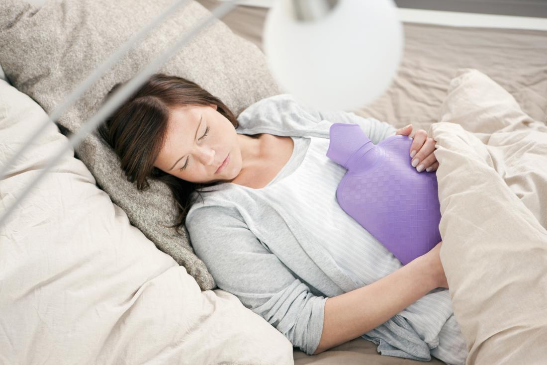 woman experiencing period pains holding hot water bottle