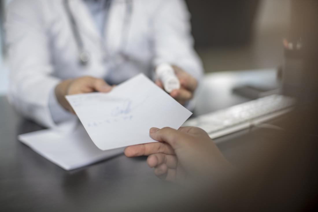 Doctor handing written prescription to patient