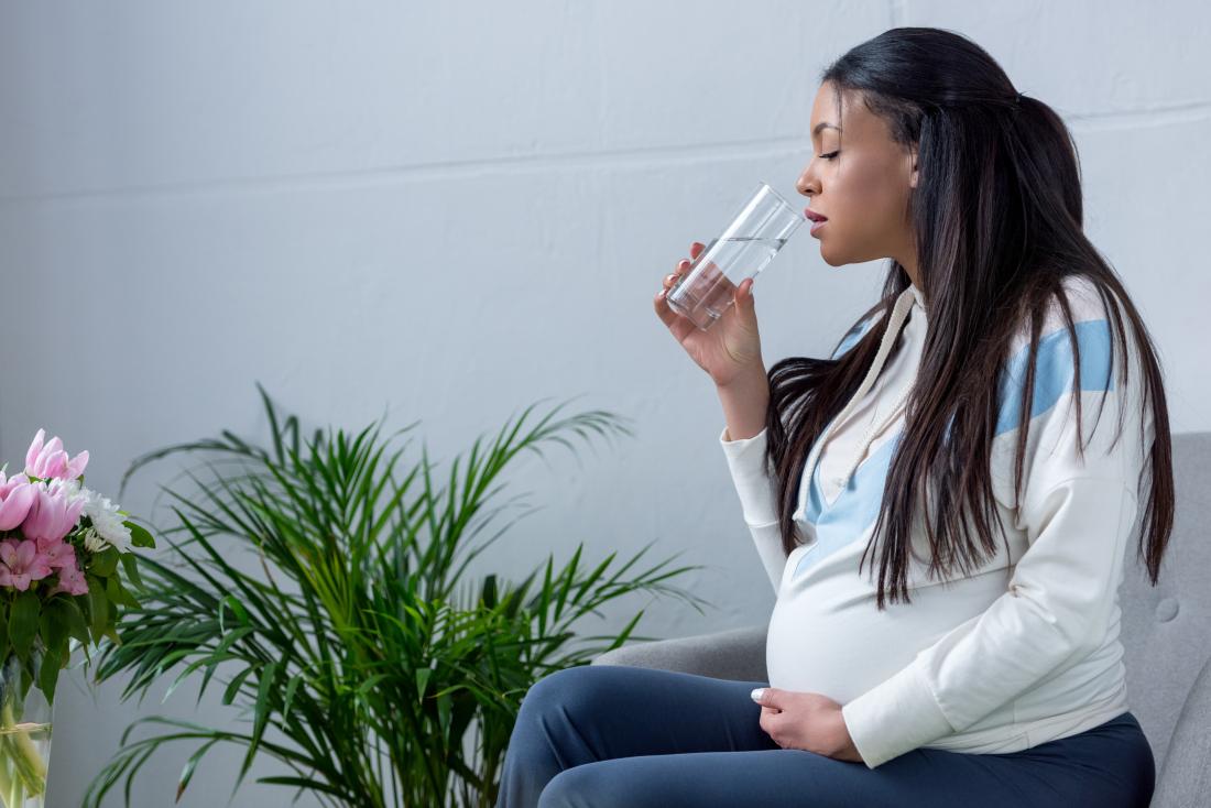 Pregnant woman with gestational diabetes drinking glass of water