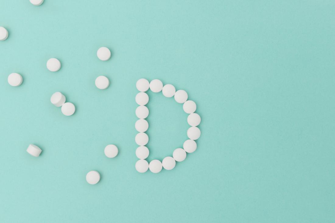vitamin D shape made of pills on blue background
