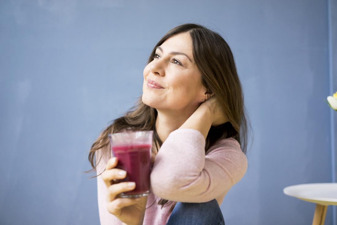 woman drinking a glass of red juice