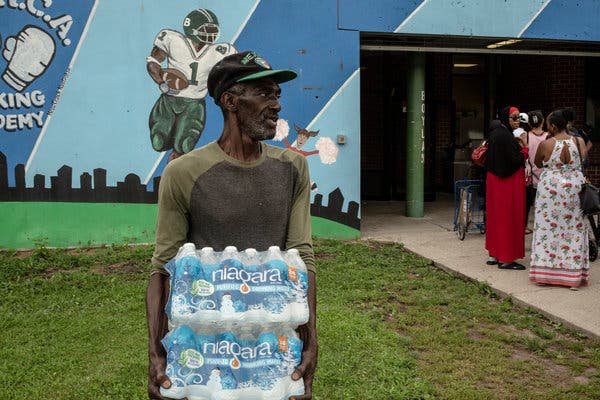 Wayne Spann carried water to residents’ cars at a distribution center in Newark.