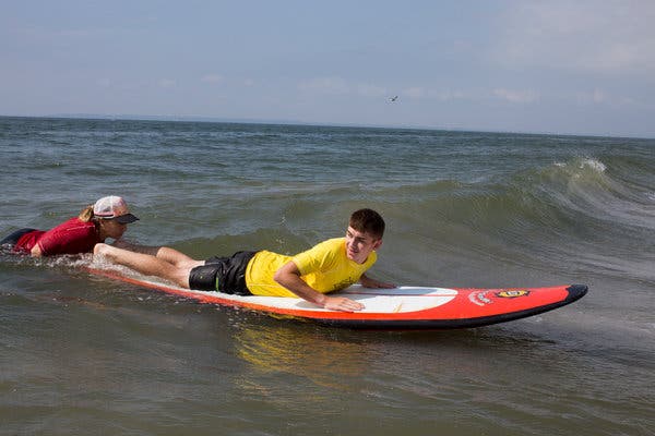 Colton Slife, 13, whose father is a retired Marine, learns to surf during AmpSurf’s clinic at the Breezy Point neighborhood of Queens in July.
