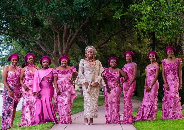 Dola Olutoye posed with her bridesmaids in traditional Nigerian attire and matching geles, a scarf or fabric folded into an ornate shape atop a woman’s head.
