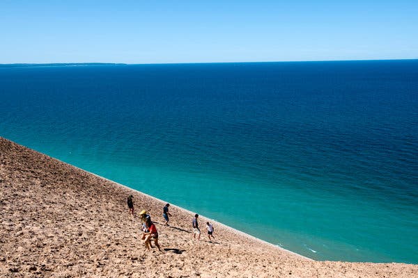 Visitors explore a steep, 400-foot-high sand dune at Stop 9 along the Pierce Stocking Scenic Drive, a seven-mile blacktop road that leads cars and cyclists through the park&rsquo;s wooded hills and towering dunes.