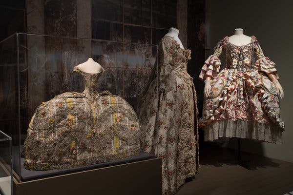 From left, two dresses from about  1755-1760 and a fall 2000 haute couture design by John Galliano for Christian Dior with an underskirt and a metal frontpiece.