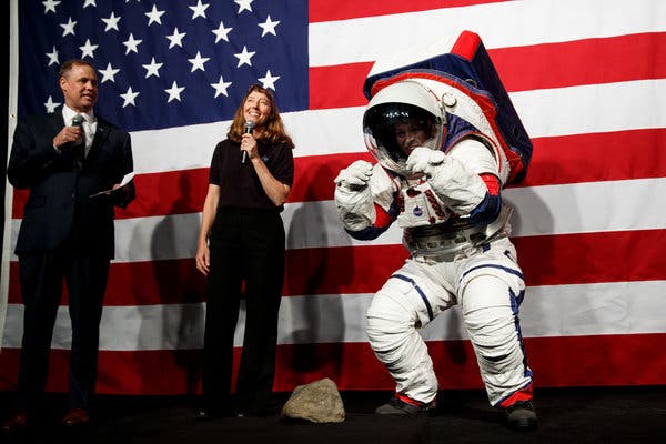 Kristine Davis, right, a NASA engineer, demonstrating the improvements in a new spacesuit for the moon that make it easier for astronauts to move around. 