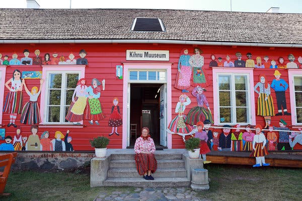 Maie Aav, the director of the Kihnu Museum, sits in front of the brightly adorned building.
